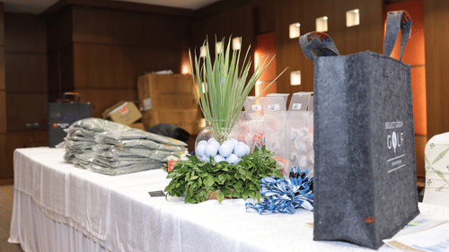 A gift bag stands tall on a table laden with neatly arranged items. - Heritage Village Resorts & Spa