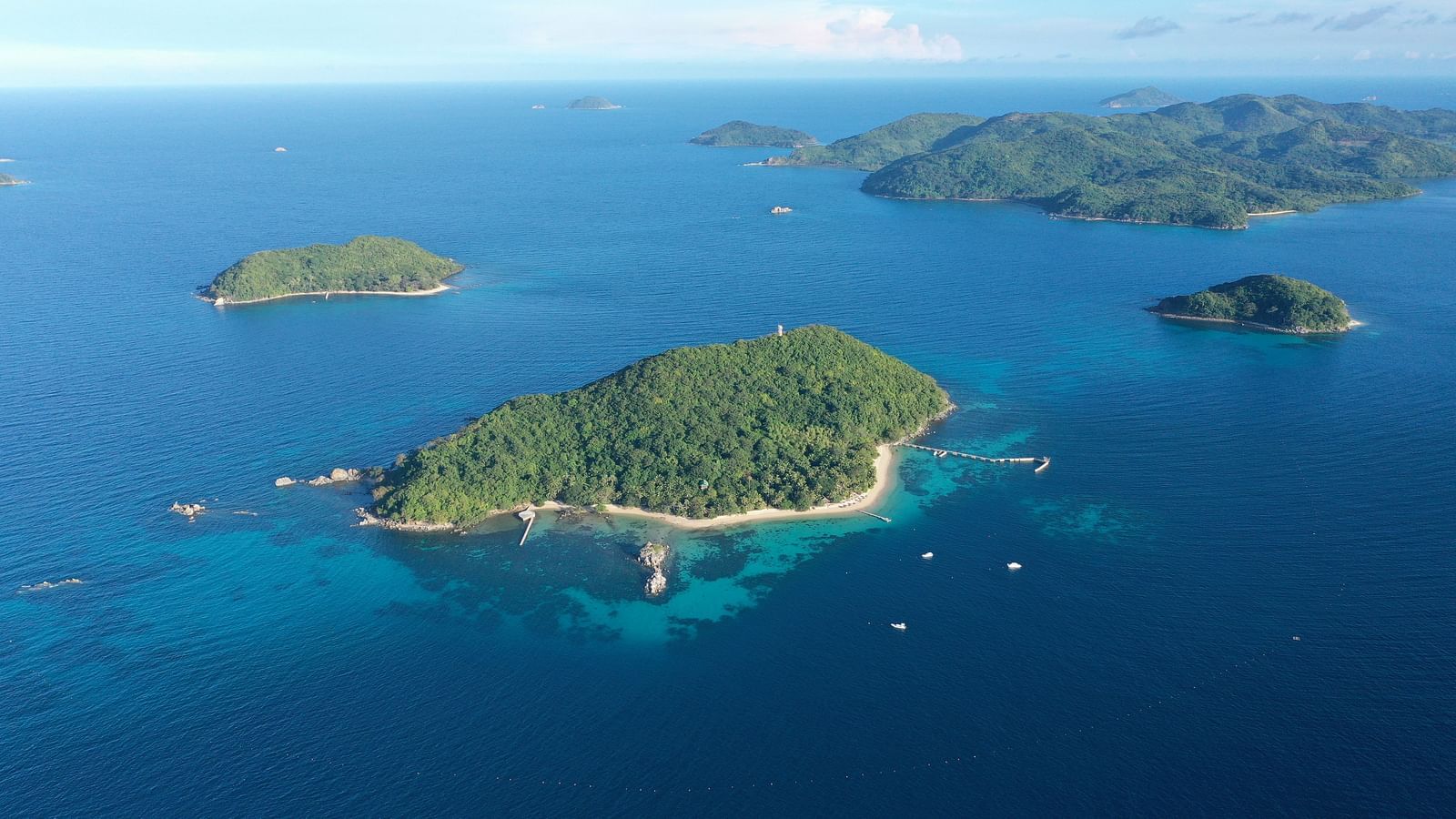 Aerial view of several green islands surrounded by blue water near Flower Island Resort.