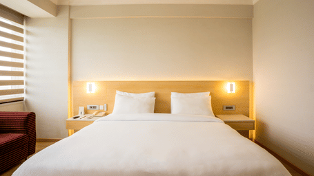 A Luxury Room with a big bed, 2 side tables, a wooden headboard and a sofa at Gemini Continental.