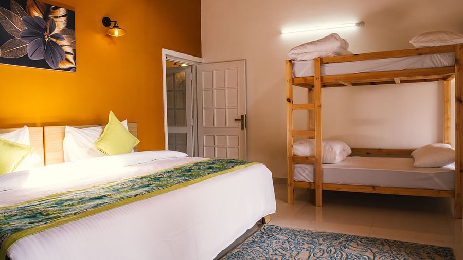 A long view of a spacious room with a large bed on one side and a bunk bed on the other at BluSalzz Villas - The Green Roof, Bhimtal.