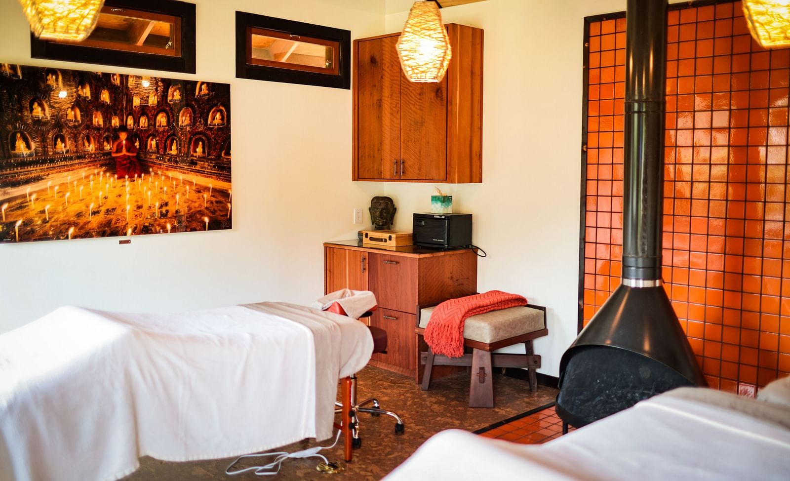 A cozy massage room featuring a hanging fireplace and massage beds - Brewery Gulch Inn & Spa