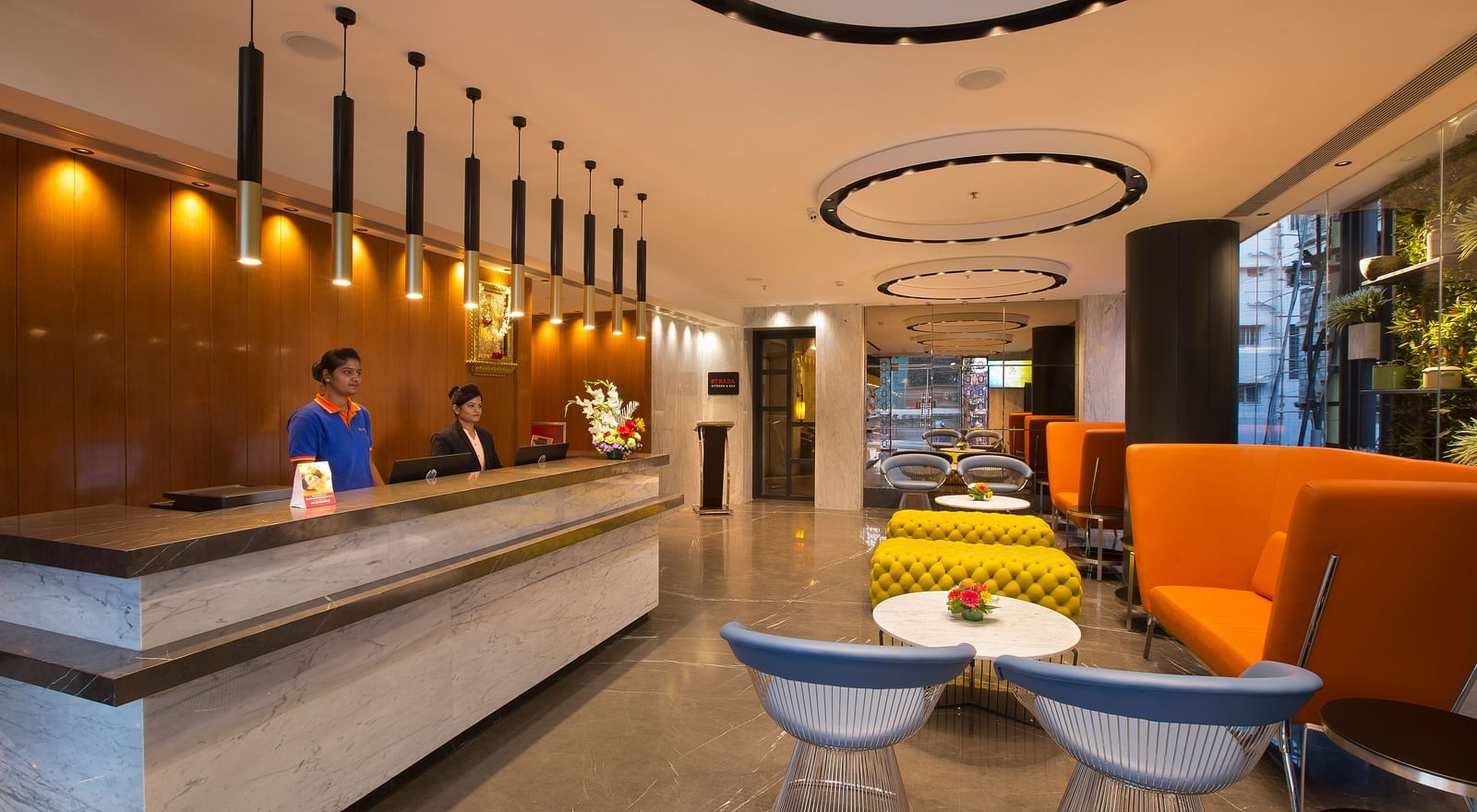 A modern hotel reception area with bright orange and yellow seating, a dark wooden front desk and pendant lights - Hotel Southend by TGI - Bommasandra, Bangalore