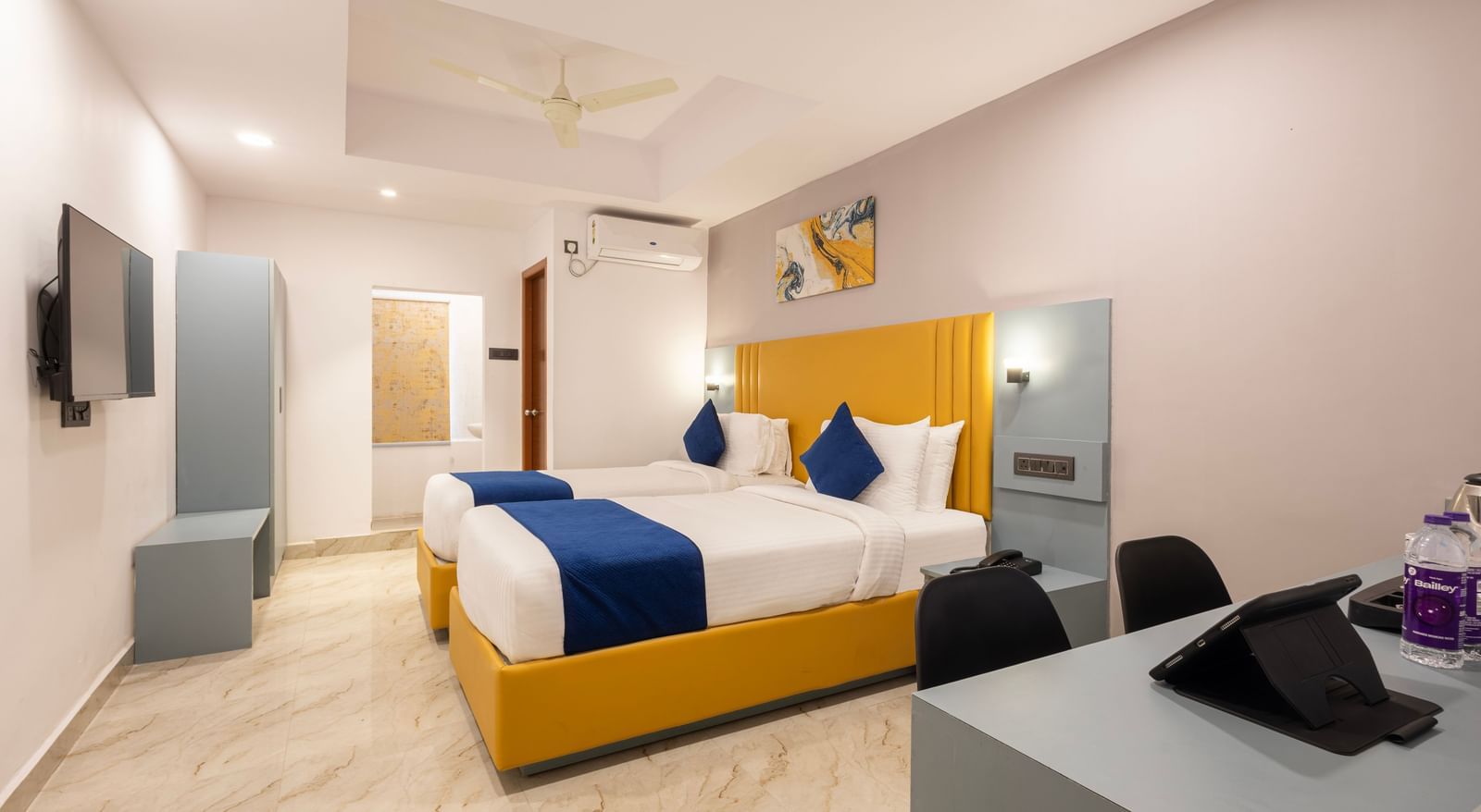 Superior Room featuring a bed with blue and white bedding, a yellow headboard, and modern furnishings including a desk and TV - Beestay Hotel Financial District, Hyderabad