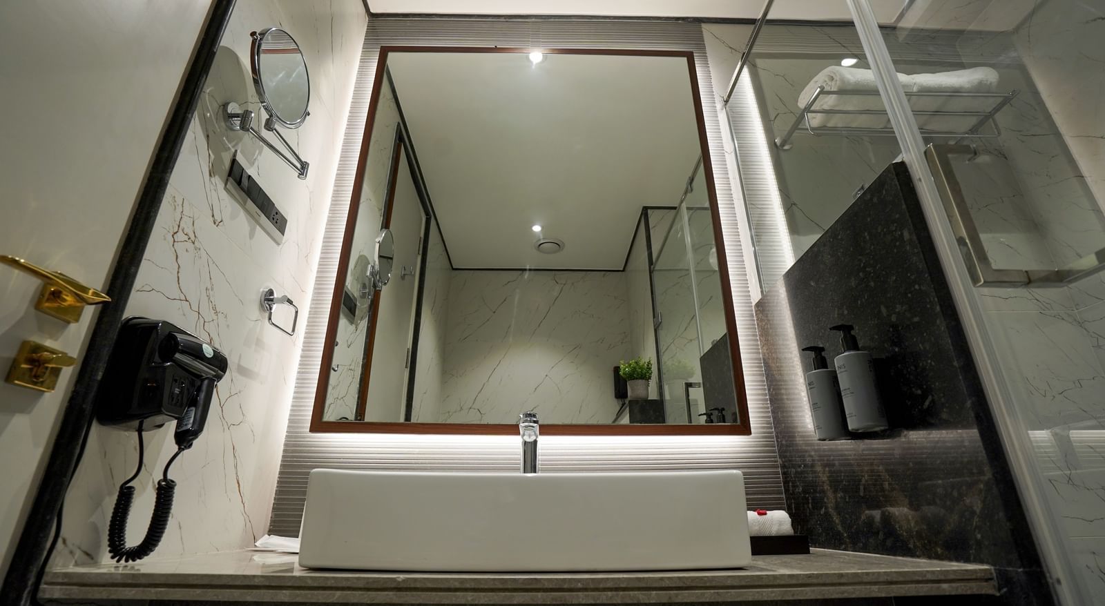 A sleek bathroom featuring a washbasin and a back-lit mirror in the bathroom of the Premium Room at M2 Square by Monday Premium.