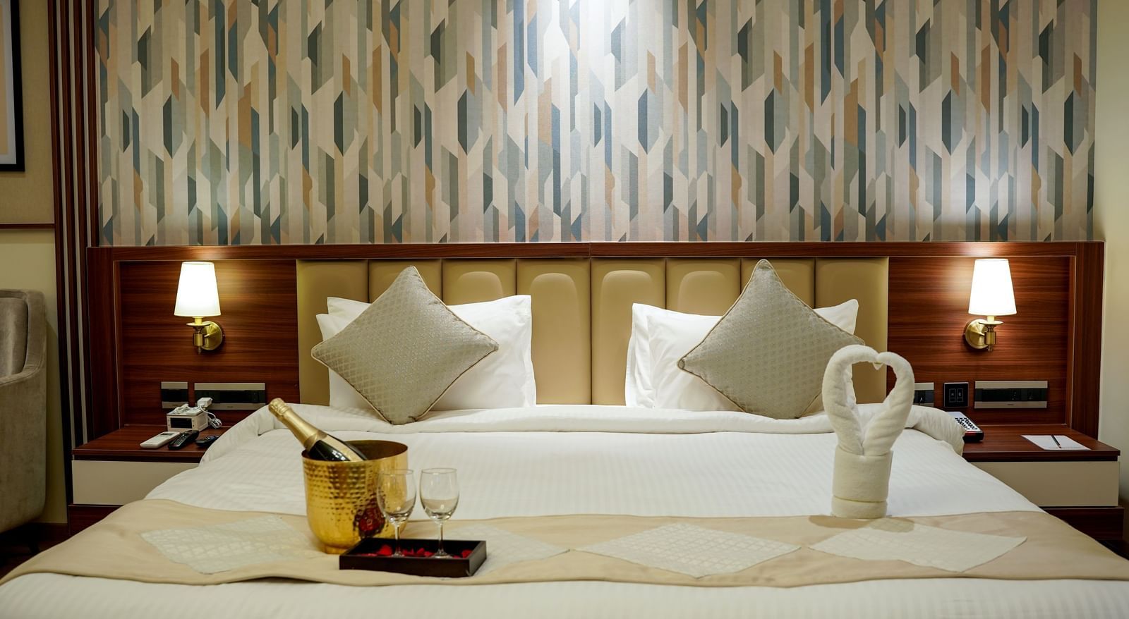 Front view shot of a double bed featuring an ice bucket with a bottle of champagne kept on the bed in the Premium Room at M2 Square by Monday Premium.