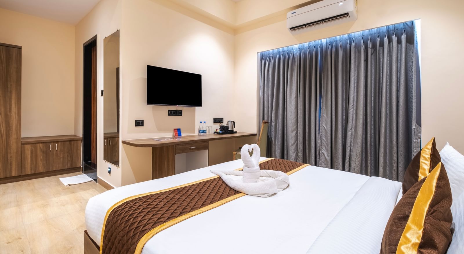 Spacious room at Monday Hotels Amalapuram Heights with TV, curtains, and double bed.