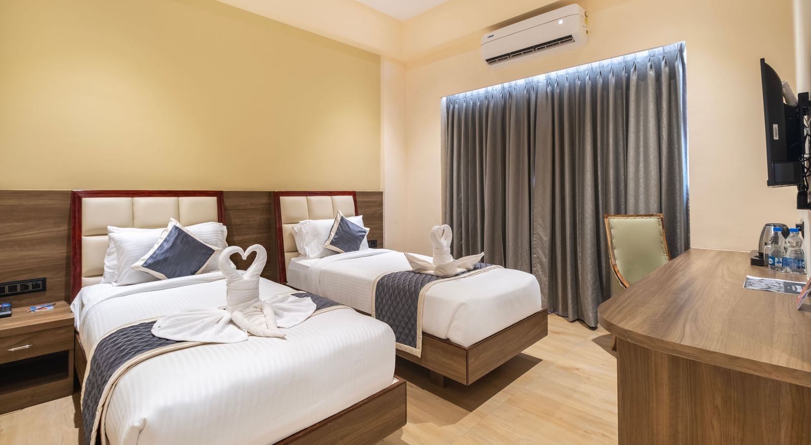 Twin bed room at Monday Hotels Amalapuram Heights with window and air-conditioning.