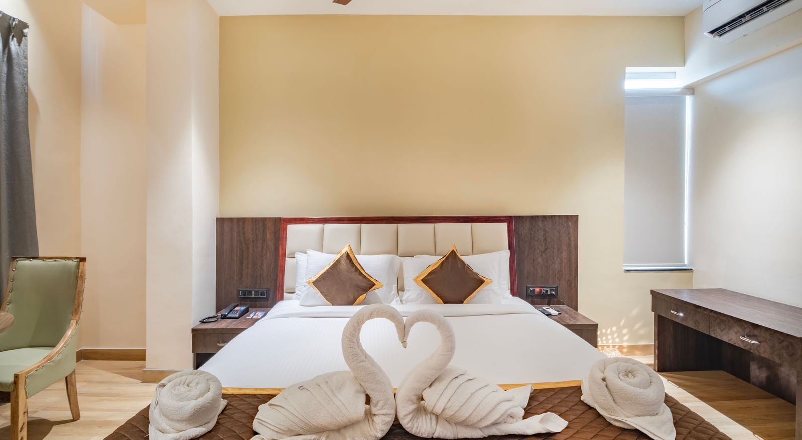 Deluxe room at Monday Hotels Amalapuram Heights with swan towel decor on bed.