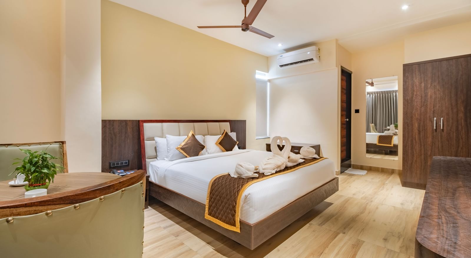 Spacious room at Monday Hotels Amalapuram Heights with double bed, ceiling fan, mirror, and air-conditioning.