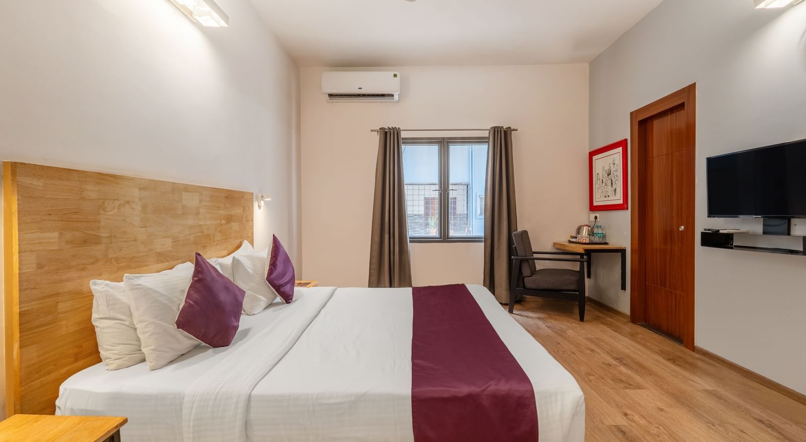A hotel room with a double bed, a wall-mounted TV, and a window with the curtains opened - Monday Hotels HITEC City, Hyderabad
