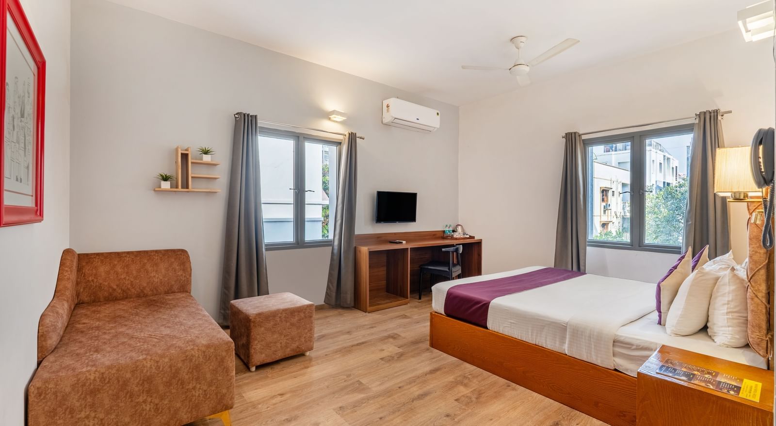 A hotel room with a bed, a seating area, and a wall mounted tv – Monday Hotels HITEC City, Hyderabad