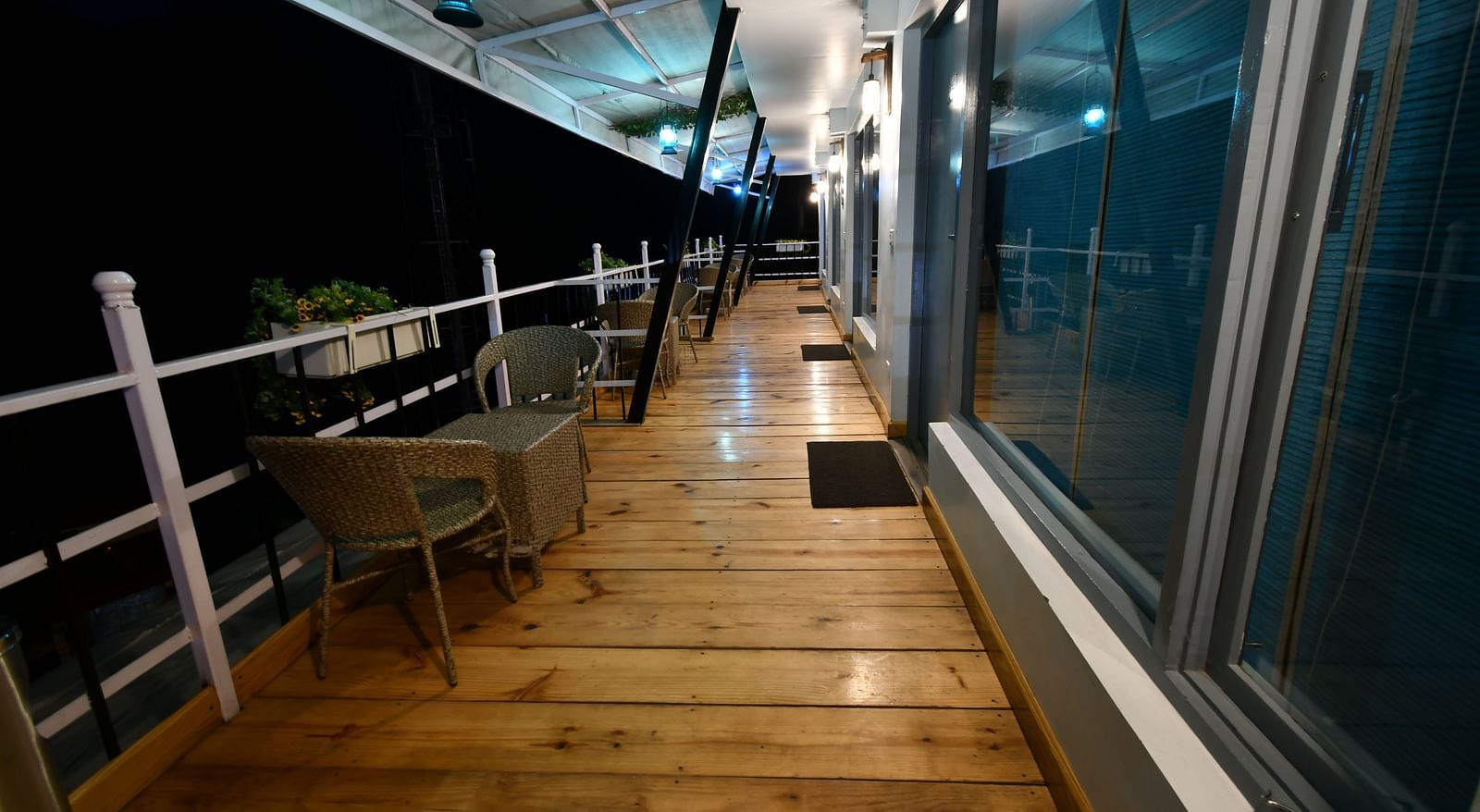 full view image of the balcony in the premium room with wooden flooring during the night - The Tattva Boutique Resort