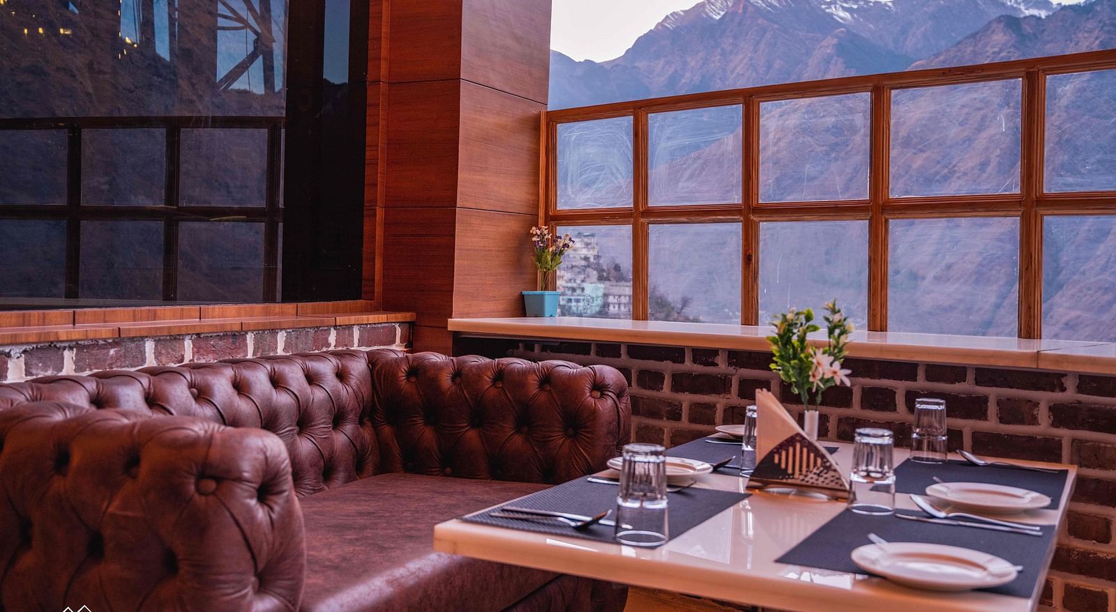 image of a maroon leather sofa with a dining table in front of it at the alpenrose restaurant - the tattva boutique resort
