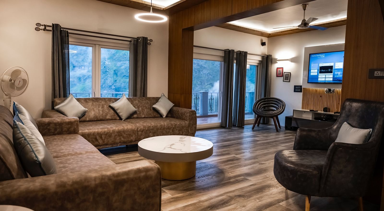 image of the living room of the pent house with a cushioned sofa and a round coffee table in front of it - The Tattva Boutique Resort