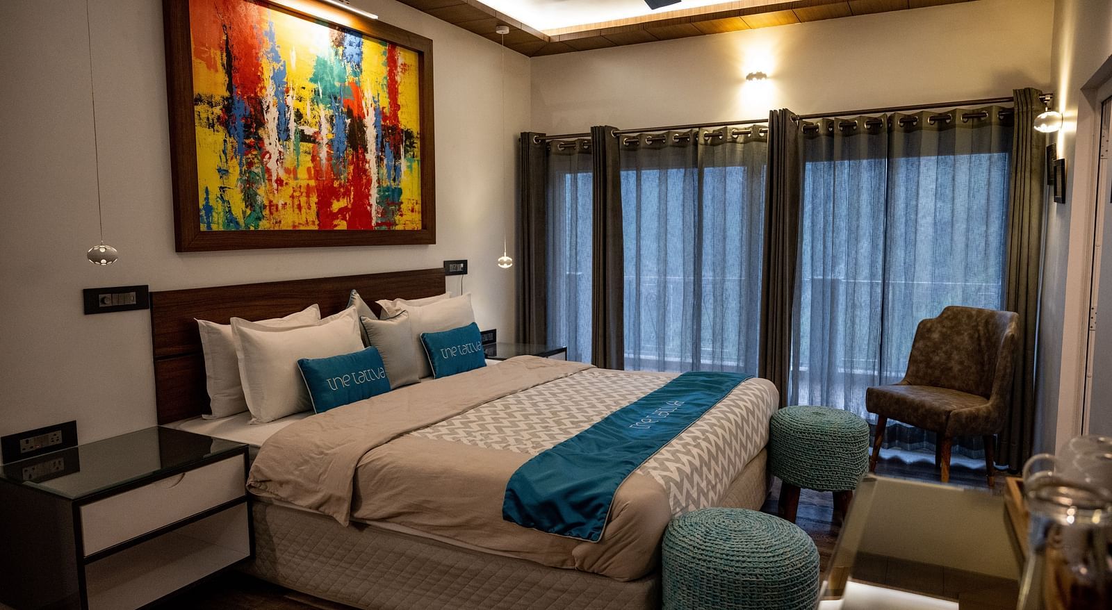 image of the bedroom at the pent house featuring a beautiful painting hung above the bed - The Tattva Boutique Resort