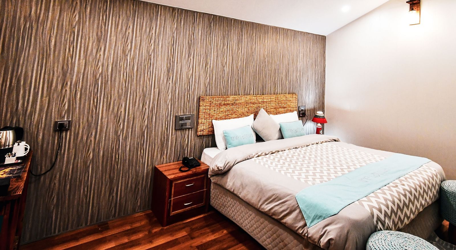 image of the standard room featuring a double bed in the corner with wooden flooring - The Tattva Boutique Resort