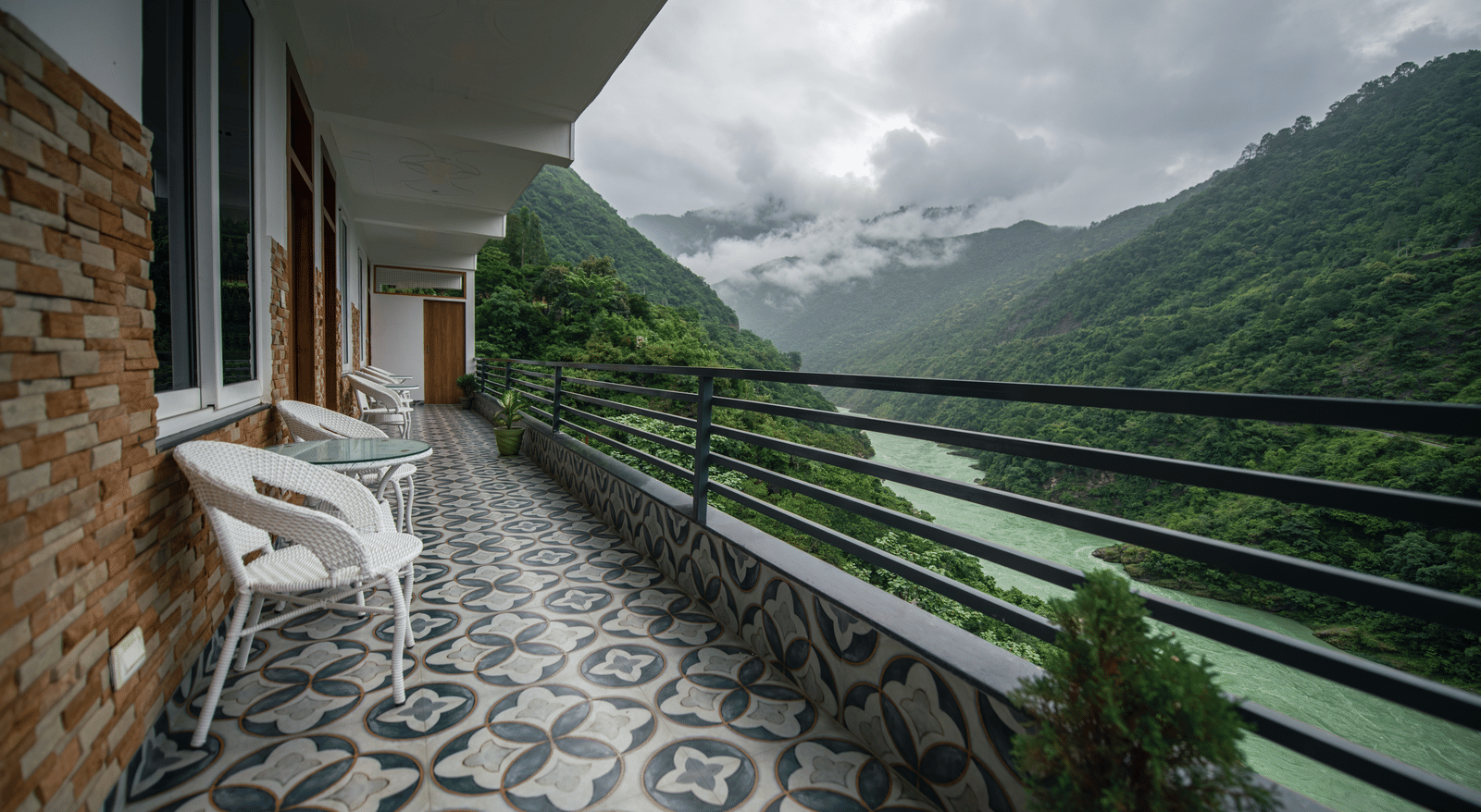 A balcony of a Deluxe Room at The Tattva Devaprayag with a view of the mountains and the river.