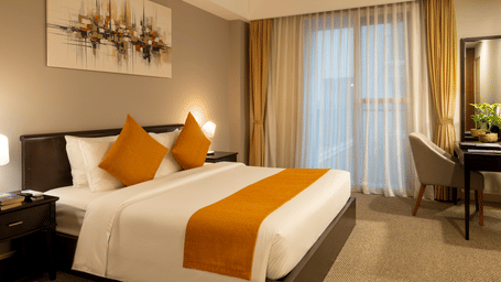 One Bedroom Suite bedroom at Central Mansions, Phnom Penh with a king bed, work desk, and large windows.