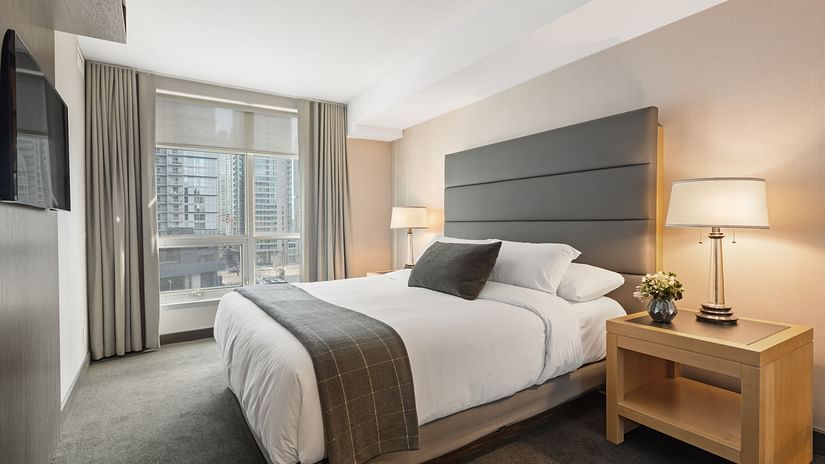 A double bed with cushioned headboard and a side table with a lamp on it