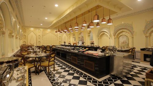 A buffet stretches across a checkered floor, laden with dishes under warm lights. - Heritage Village Resorts & Spa