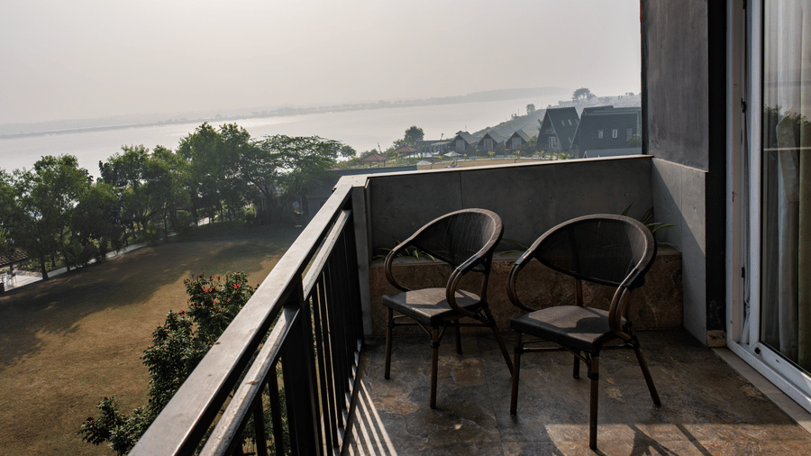 Balcony view with outdoor chairs overlooking green surroundings at Hotel Sonar Bangla, Taki.