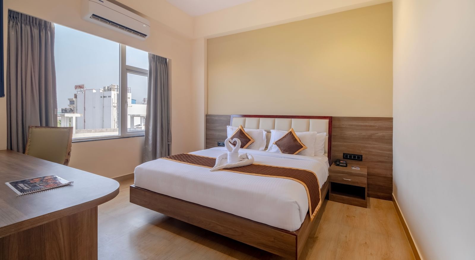 Spacious room at Monday Hotels Amalapuram Heights with double bed, bed-side table, and air-conditioning.