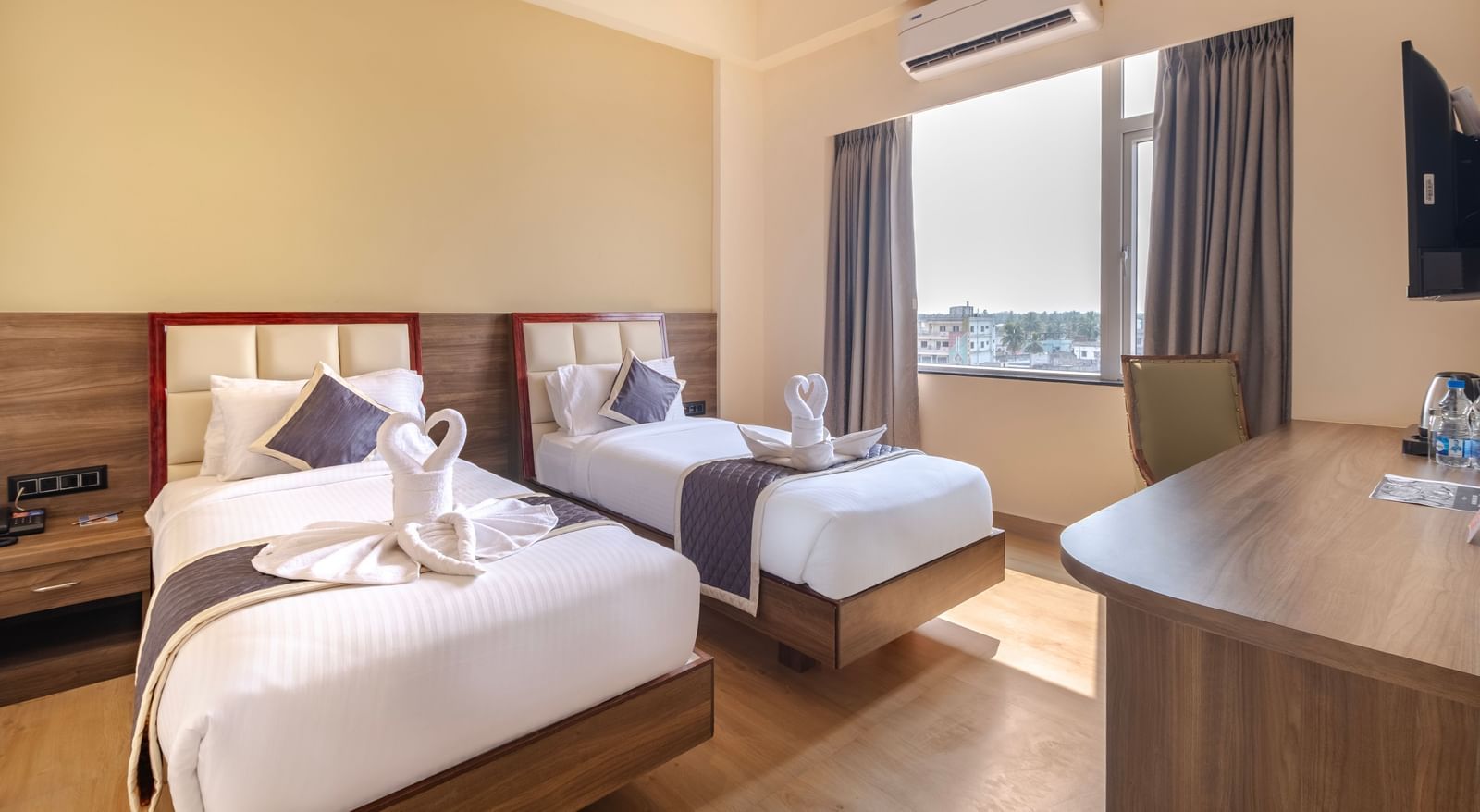 Spacious room at Monday Hotels Amalapuram Heights with warm tones, twin bed, air-conditioning, and window view.