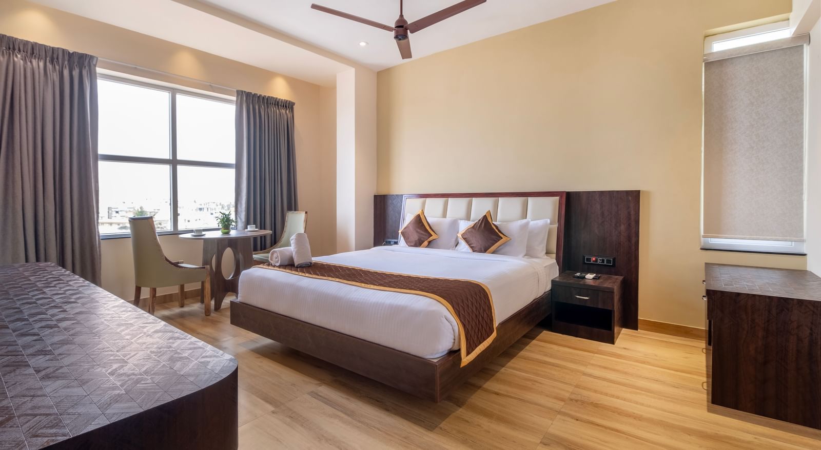Spacious room at Monday Hotels Amalapuram Heights with modern furnishings, ceiling fan, and a seating area.