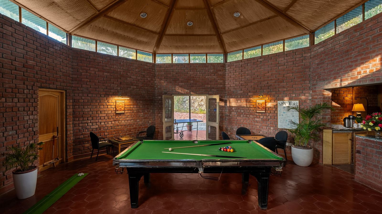A pool area with a glass roof, indoor plants and room is illuminated by lights -  Baikunth resort, kasauli 