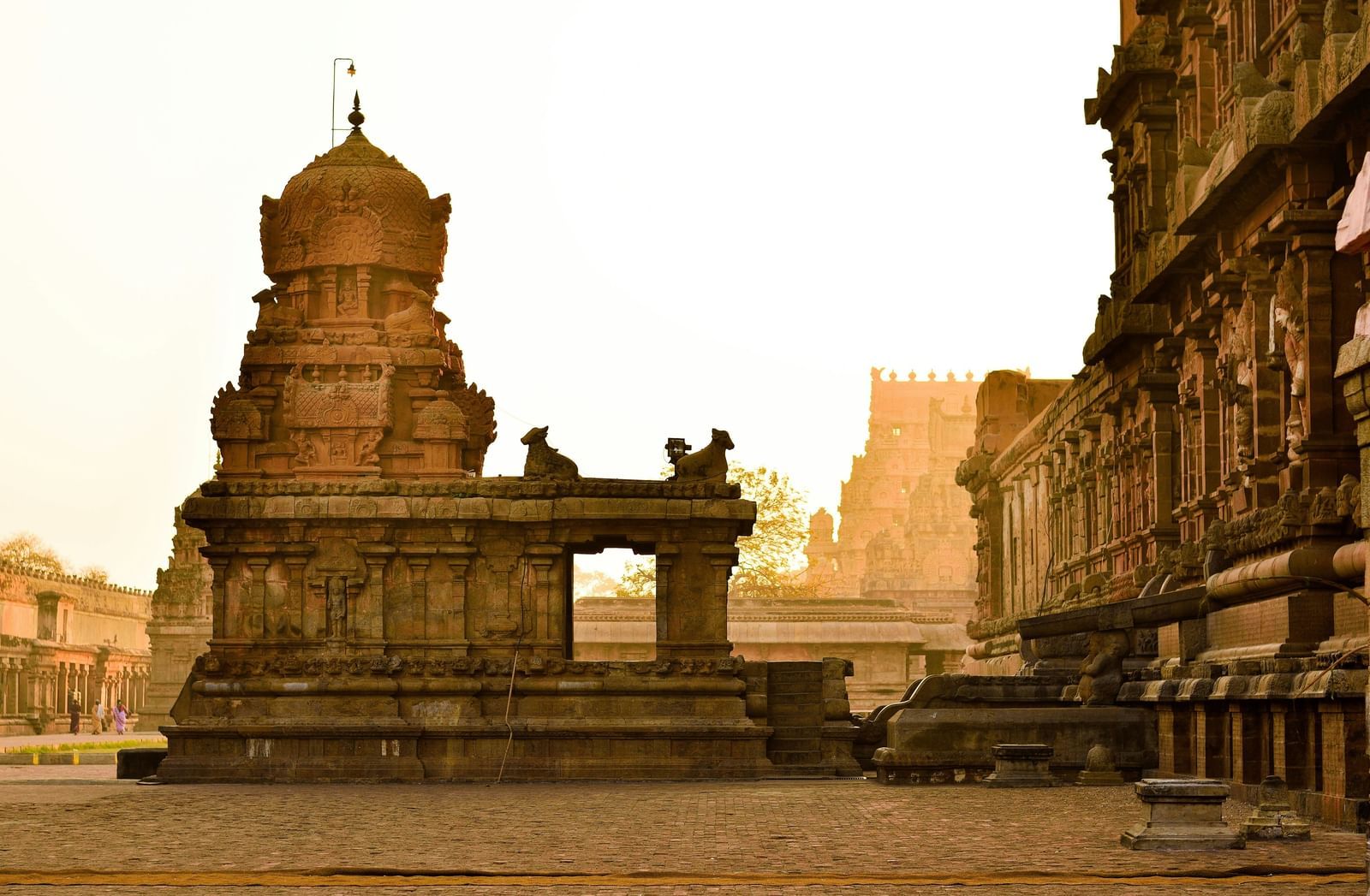 A wide-angle, low-angle shot of a temple, featuring a grand, ancient stone structure with detailed carvings and a traditional design, set against a clear sky.
