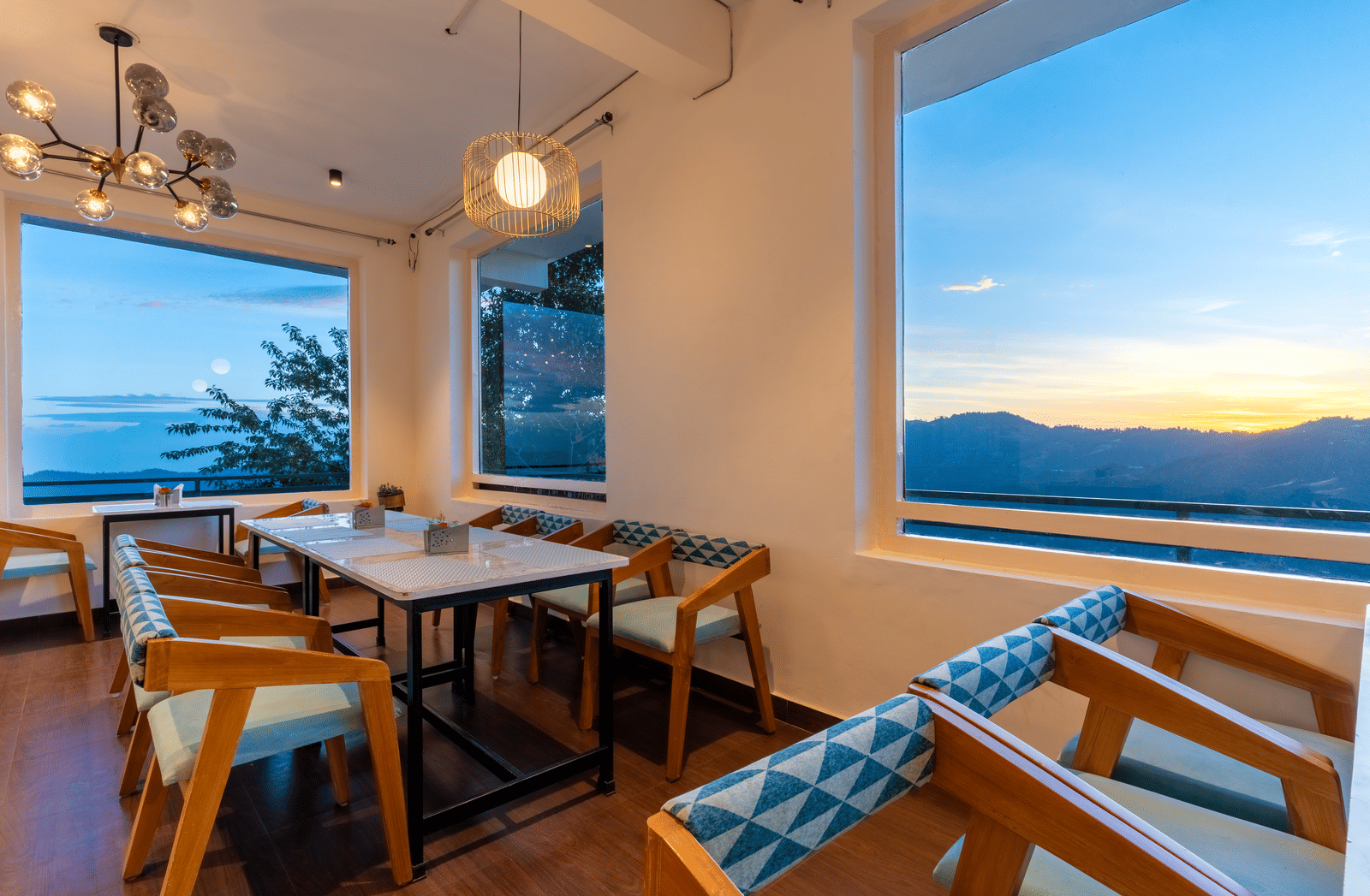 A view of the sunlit dining area with wooden furniture at Himalayas Resort By The Lake Hill, Mukteshwar during sunset.