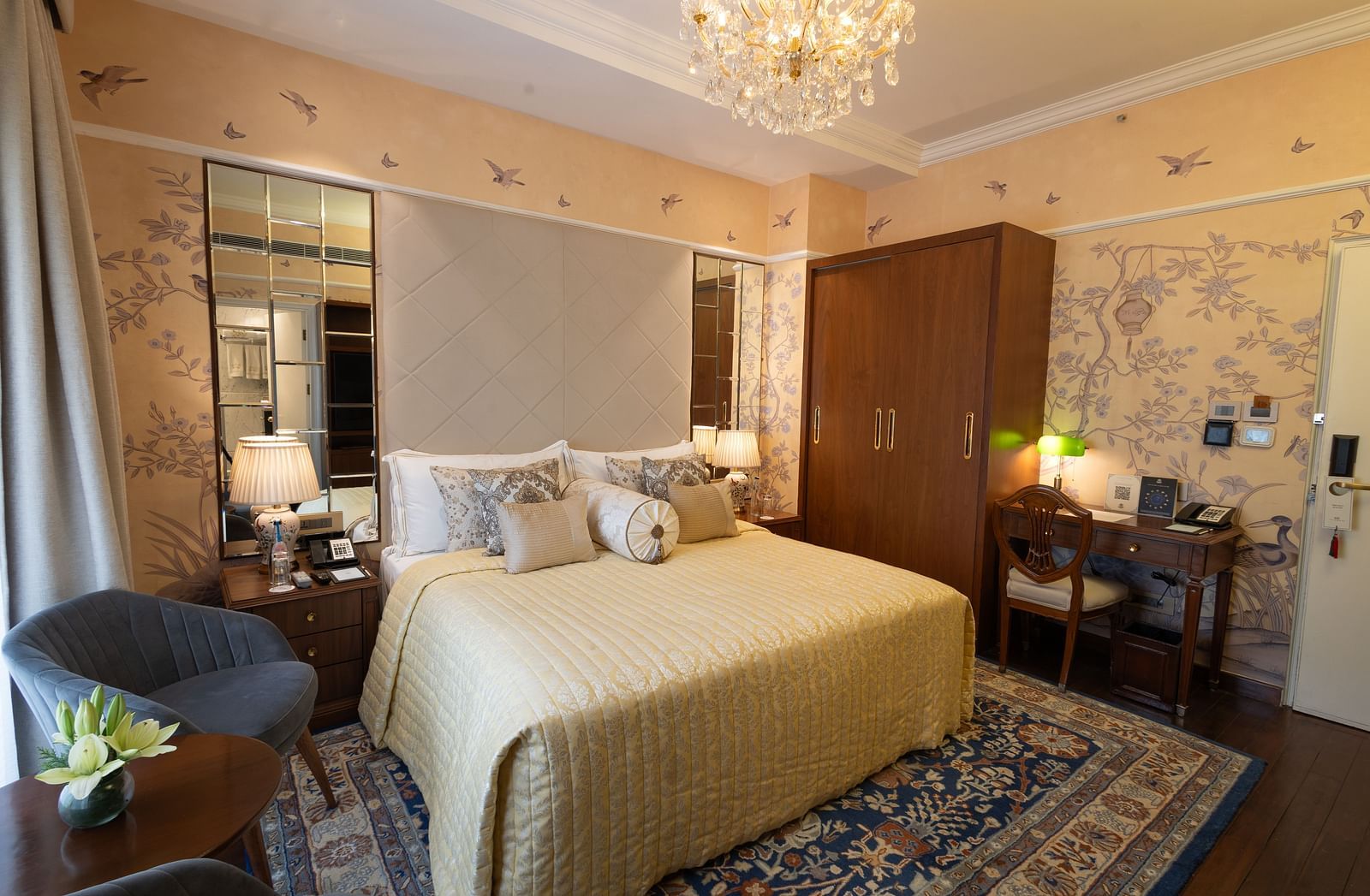 Luxury King Bed Room with Balcony at The Claridges New Delhi, featuring a cosy bed with bedside lamps and a chandelier hanging above