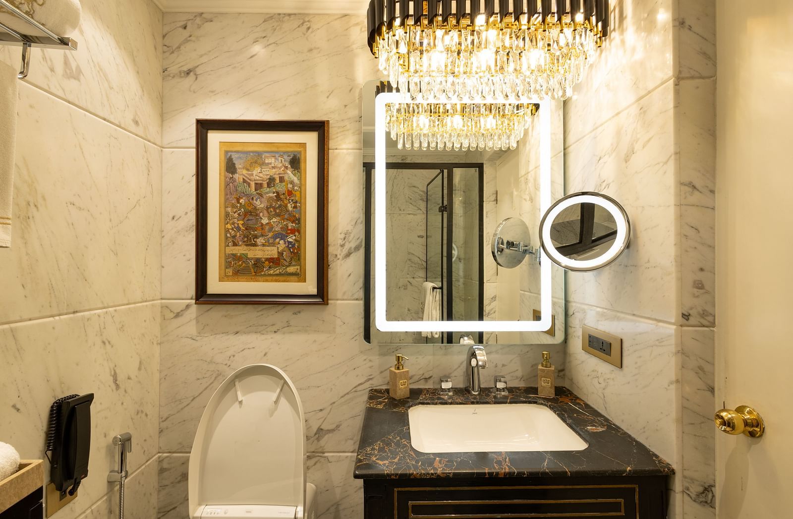 Washroom of Luxury King Bed Room with Balcony at The Claridges New Delhi, featuring a sleek sink, wall-mounted mirror, and an elegant chandelier hanging overhead