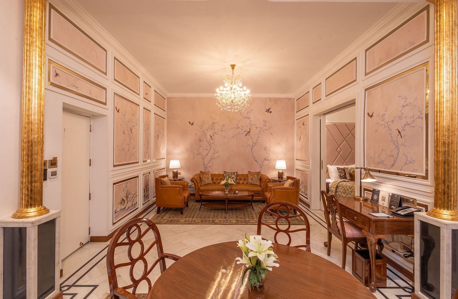Luxury Suite at The Claridges New Delhi, featuring a corner view of the room with a cosy sofa set and an elegant chandelier hanging overhead
