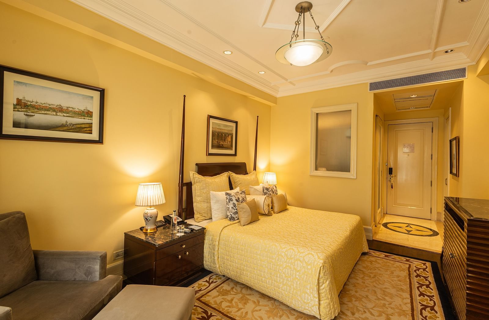 Side view of the Deluxe King Bed Room Pool View at The Claridges New Delhi, featuring a cosy king sized bed, wall-mounted TV, and bedside lamps