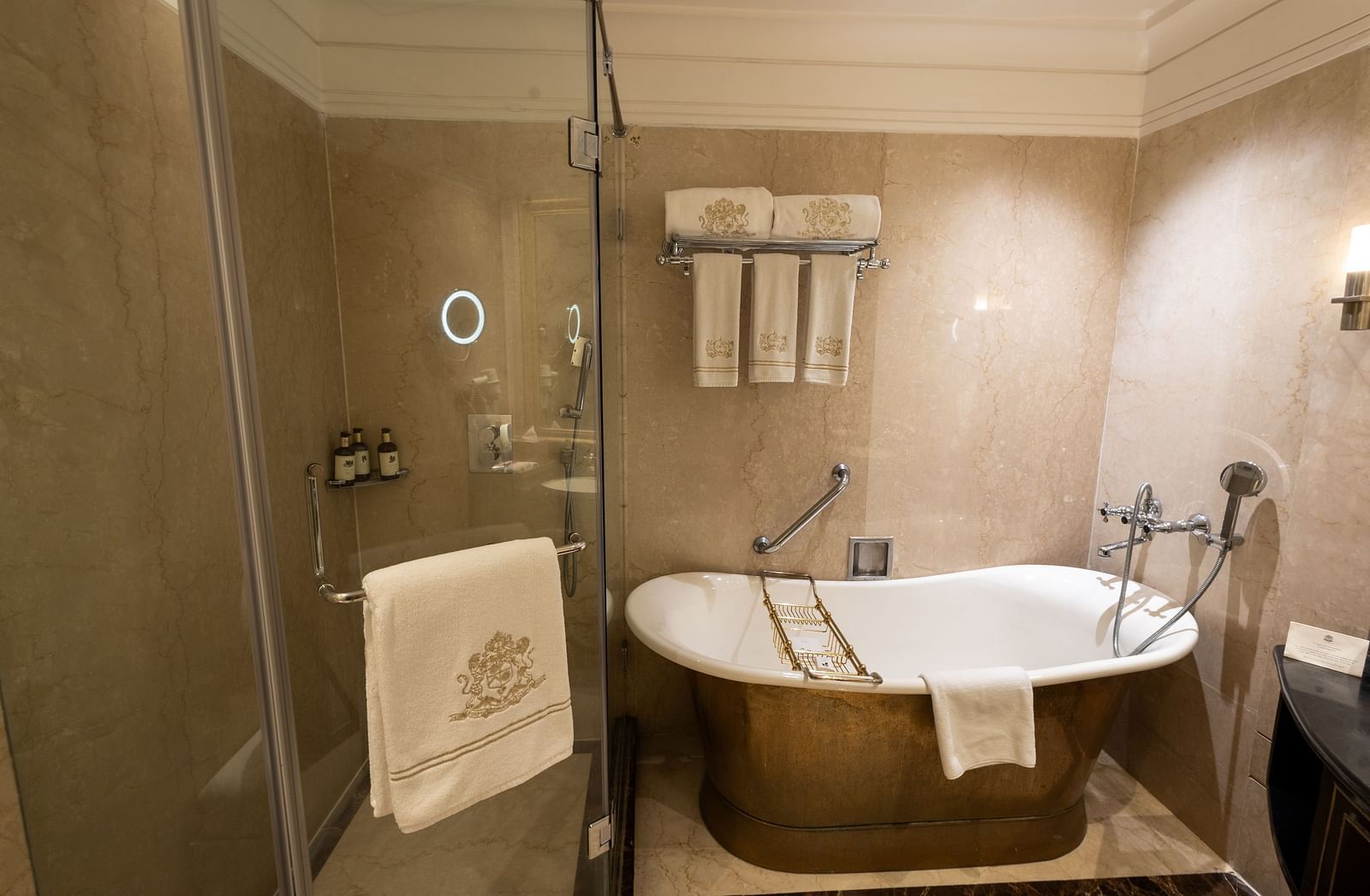 Washroom of the Grand Luxury King Bed Room at The Claridges New Delhi, featuring a stylish bathtub, glass-enclosed bath area, and a neatly hung towel on the wall
