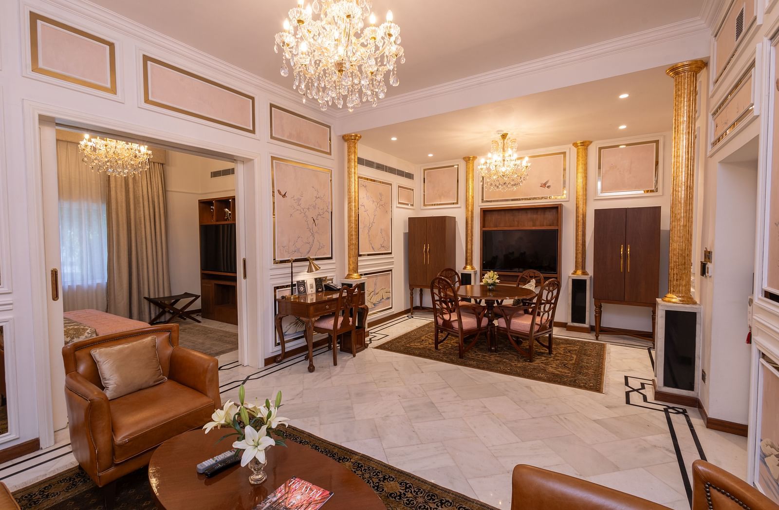 Luxury Suite at The Claridges New Delhi, featuring a spacious room with a corner sofa and a chandelier