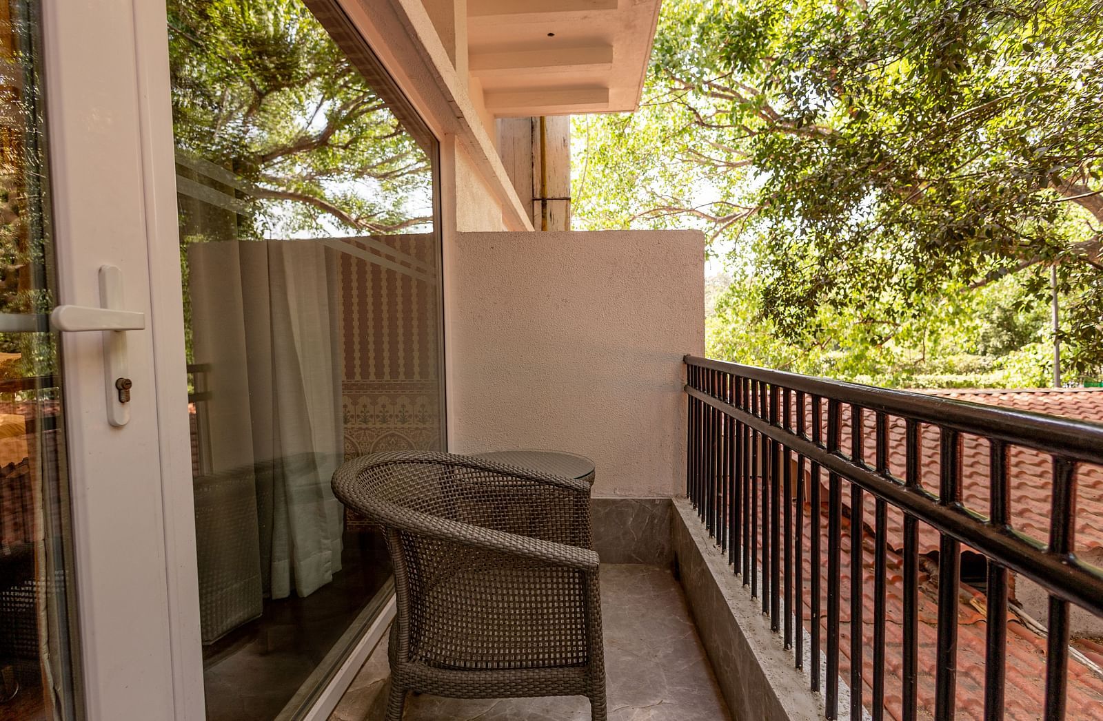 Balcony of the Luxury Twin Bed Room with Balcony at The Claridges New Delhi, featuring a comfortable chair and a glass door