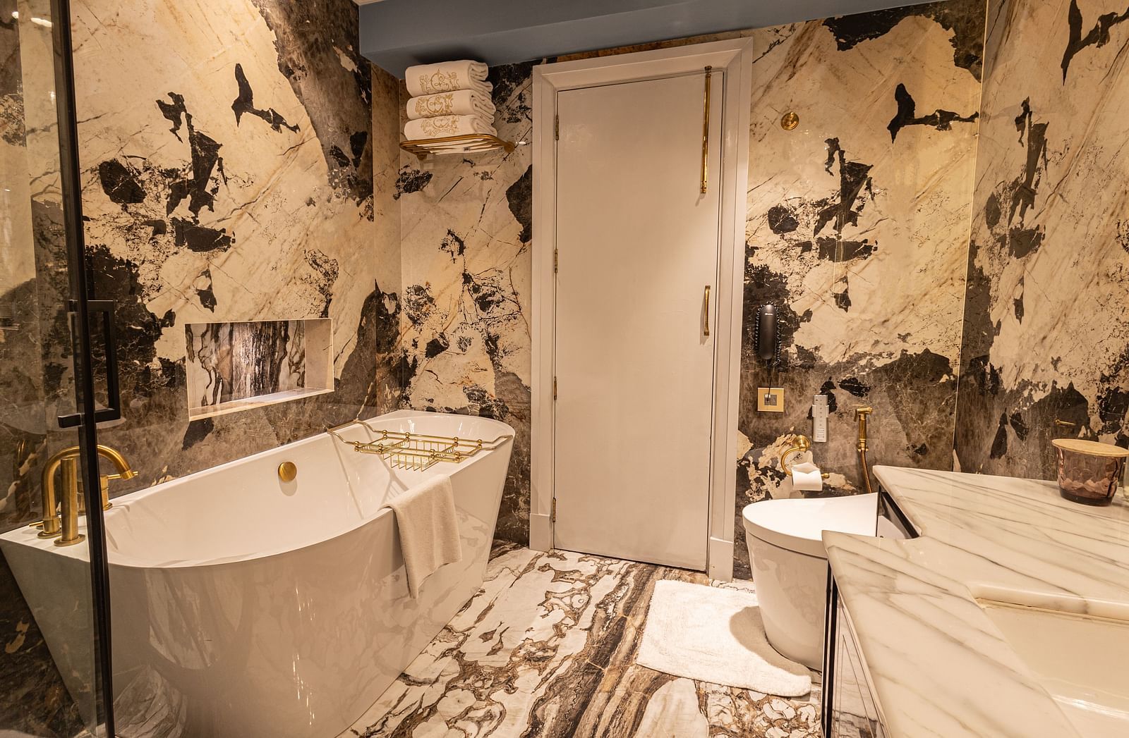 image of a luxurious bathroom with a bathtub at one side with white and black marble on the walls at the heritage parlour suite - The Claridges New Delhi