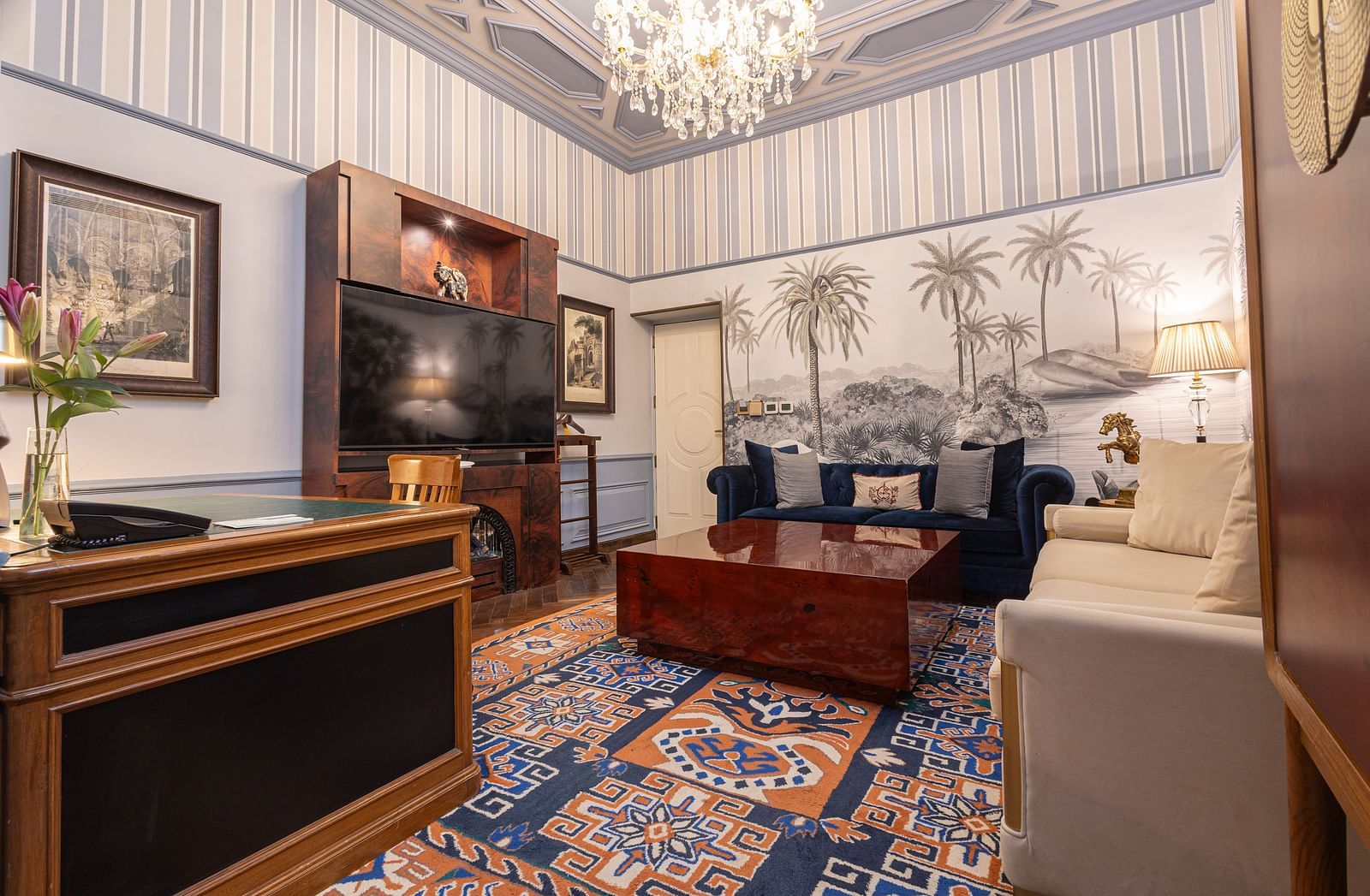 image of the living area from a corner of our heritage parlour suite with a wall mounted television in front of the couch - The Claridges New Delhi