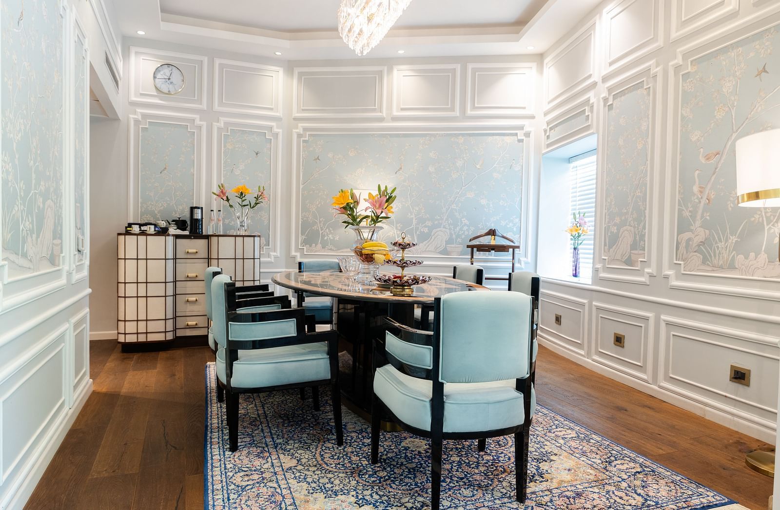 A dining table with blue cushioned chairs on either side in the living area of our Diplomatic suite in New Delhi at the Claridges