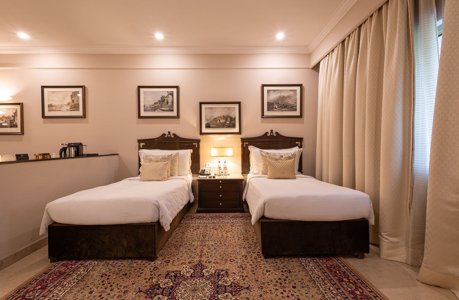 Front view of the Grand Luxury Twin Bed Room at The Claridges New Delhi, featuring elegant twin beds, a framed photo on the wall, and stylish ceiling lights