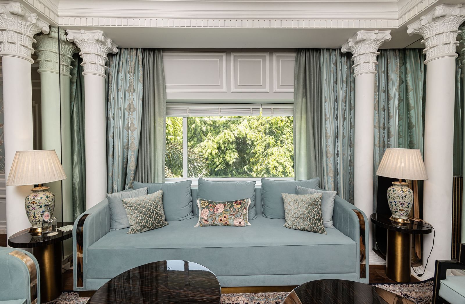 An image of a blue couch with lamps placed on either side of it at the Diplomatic suite room - The Claridges New Delhi