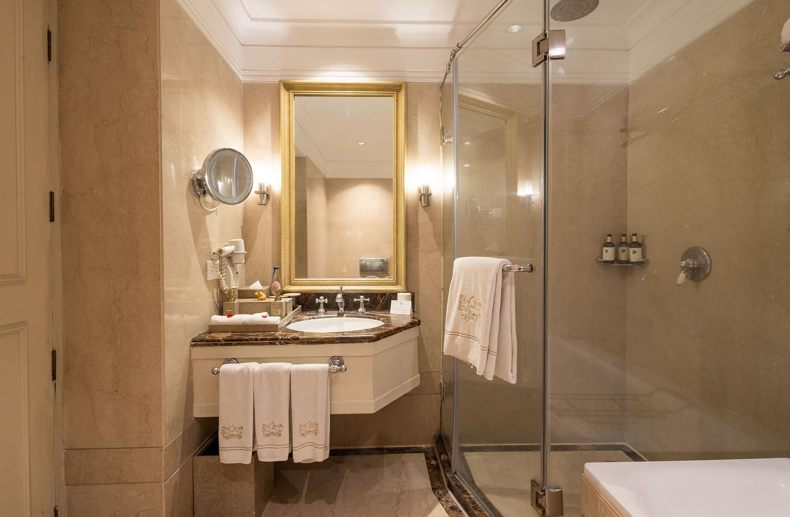 Washroom of the Grand Luxury Twin Bed Room at The Claridges New Delhi, featuring a modern sink, a wall-mounted mirror, and a glass-enclosed bath area