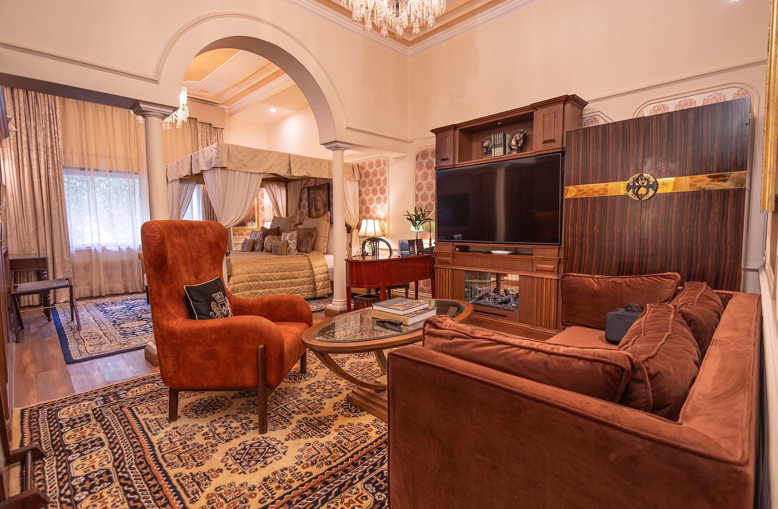 image of the family seating area inside the bedroom of the heritage parlour suite with brown couch and a centre table in front of it with wall mounted tv - The Claridges New Delhi