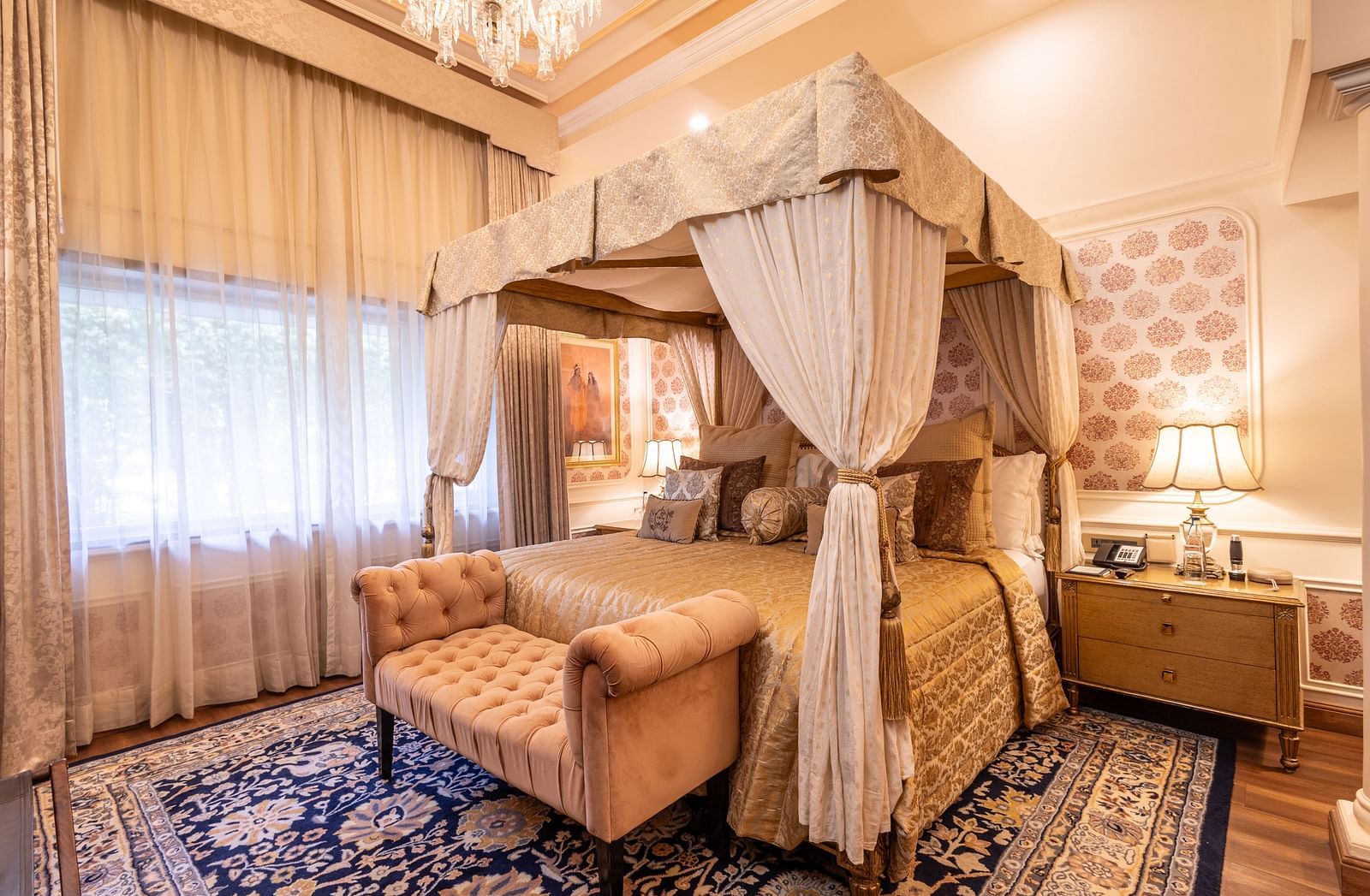 A regal bedroom showcasing a king-size bed surrounded by rich, thick curtain drapes that add a touch of opulence in the Heritage Parlour Suite - The Claridges New Delhi
