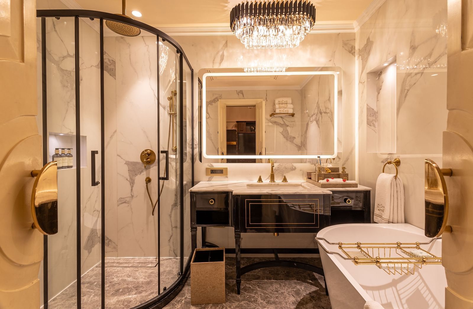 image of a brightly lit luxurious bathroom with a cubical shower and a bathtub at our heritage parlour suite - The Claridges New Delhi