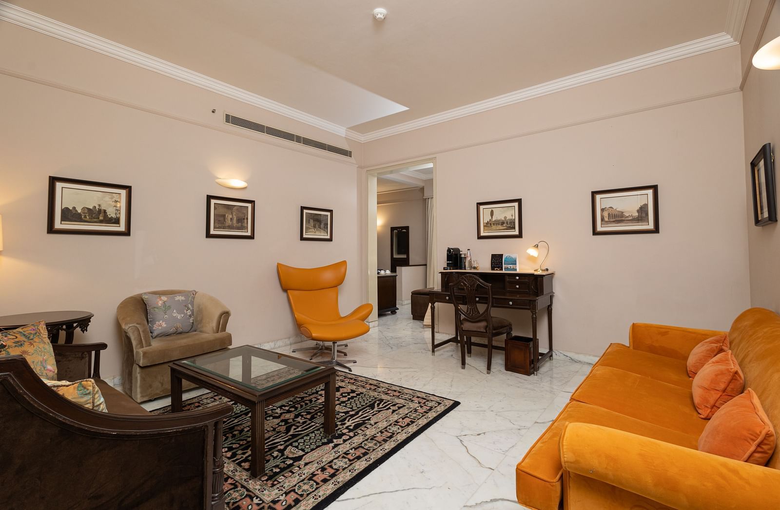 image of the living area with white marble flooring and bright yellow couch at the heritage parlour suite - The Claridges New Delhi
