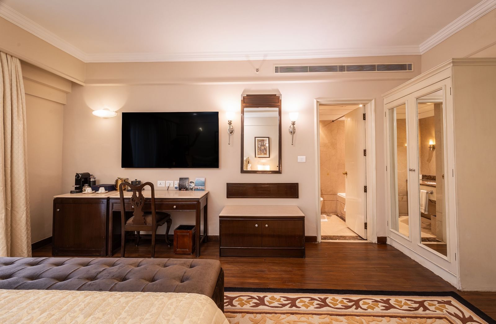 image of the heritage terrace room with a wall mounted tv and a half length mirror - The Claridges New Delhi