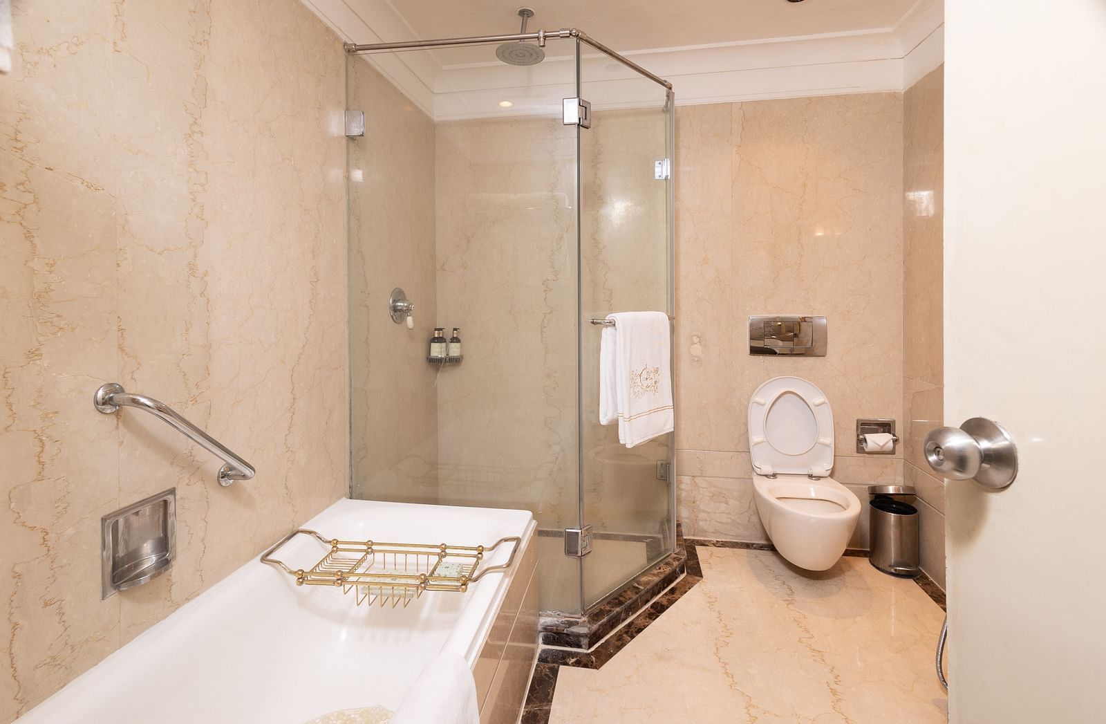 image of the bathroom with a cubical shower, a full length bathtub and a commode at our heritage parlour suite - The Claridges New Delhi